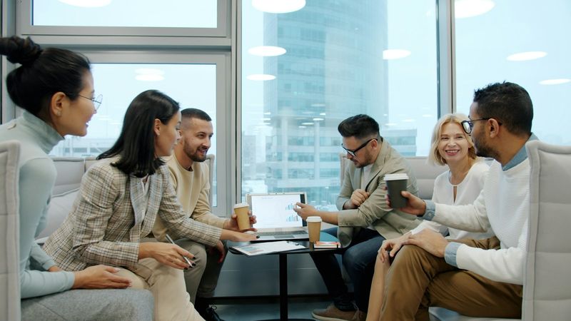 A small team laughing together around a laptop in a bright office
